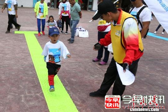 8月19日，160余徒步爱好者健步青海湖，以行走的方式倡议环境保护。图为年纪最小的健步参与者通过尖叫趾压板。　罗云鹏 摄